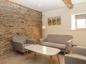 Ein Zimmer mit einer Steinsäule, zwei grauen Sofas, einem weißen Couchtisch und einer Stehlampe.
