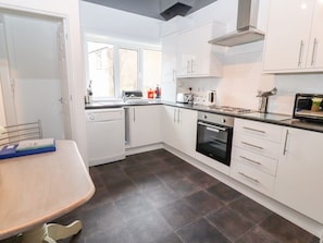 A modern kitchen with white cabinets, a black oven, and a window providing natural light. - Sea Breeze, Rhos-on-Sea (Colwyn Bay)