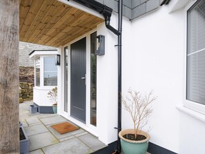 A house with a wooden porch, a black door, a potted plant, and a stone wall in the background. - Jays Nest, Bolventor, Cornwall (Launceston)