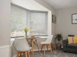 A dining area with a table and chairs, a window with blinds, a sofa, and a potted plant. - Jays Nest, Bolventor, Cornwall (Launceston)