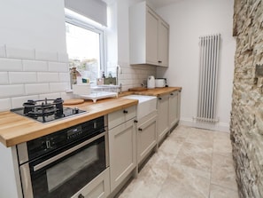 A modern kitchen with a gas stove, oven, and wooden countertop.