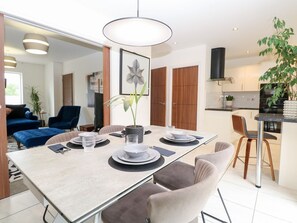 A modern dining area with a long table, chairs, and a hanging light fixture. - Manor Park View, Norwich (Norwich)