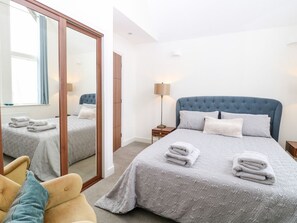 A hotel room with a large bed, a chair, a bedside table with a lamp, and a mirror. - Manor Park View, Norwich (Norwich)