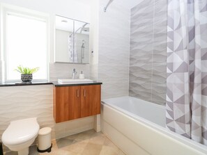 A bathroom with a toilet, sink, mirror, and shower area. - Manor Park View, Norwich (Norwich)