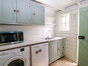 A compact kitchen with a washing machine, a microwave, and a sink. - Charming Bell 2 Property in Minety (Cirencester)