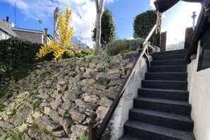 Un escalier en pierre menant à un bâtiment, entouré de verdure et sous un ciel dégagé.