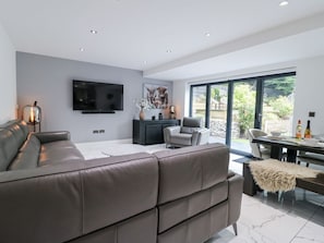 A modern living room with a leather sofa, a flat-screen TV, a fireplace, and a dining area with a table and chairs. - Rockcliffe Grange, Mansfield (Mansfield)