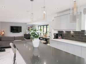 A modern kitchen with a large island, pendant lighting, and a dining area with a sofa and table. - Rockcliffe Grange, Mansfield (Mansfield)