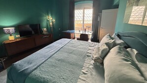 Ein Schlafzimmer mit Bett, Schreibtisch, Stuhl und Fernseher.