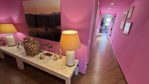 Ein Flur mit rosafarbenen Wänden, einer Holzbodenbank mit Dekoration, einer Lampe und einem gerahmten Bild.