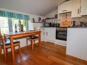 Eine Küche mit Holzausstattung, einem Esstisch mit Stühlen und einem Fenster mit Vorhängen.