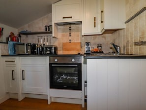 Eine Küche mit weißen Schränken, einem Einbauofen, einer Mikrowelle und einer Kaffeemaschine.