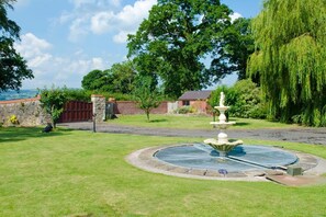A garden with a fountain, a statue, and a view of the sea. - Tall Trees, Llandyrnog, Wales. (Denbigh)