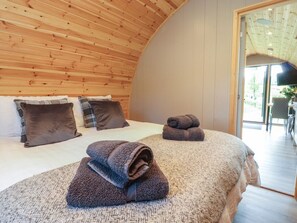 A bedroom with a curved wooden ceiling, a bed with a textured blanket, and a view of the outdoors through a glass door. - Pendle: Charming Retreat in Clitheroe (Nelson)