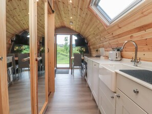 A wooden interior with a kitchen, dining area, and a view of the outdoors. - Pendle: Charming Retreat in Clitheroe (Nelson)