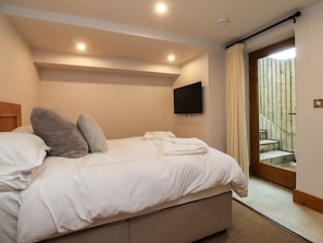Une chambre à coucher avec un lit, des oreillers, un téléviseur à écran plat et une vue sur un escalier.