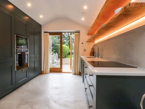 Une cuisine moderne avec des meubles de couleur sombre, un grand îlot central doté d’un évier et une vue sur l’extérieur.