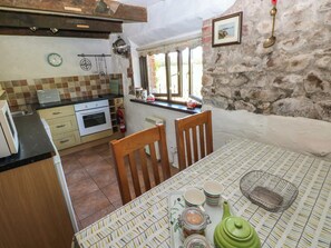 A kitchen with a tiled backsplash, wooden cabinets, a stove, and a window with a view.