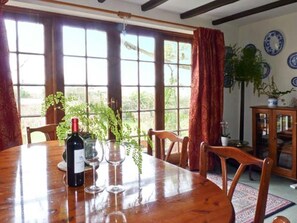 A dining area with a wooden table, chairs, a bottle of wine, and wine glasses. - Coles Cottage: Family Retreat in Holsworthy (Holsworthy)