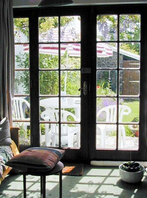 A room with a large window, a chair, a small table, and a potted plant. - Coles Cottage: Family Retreat in Holsworthy (Holsworthy)