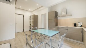 A modern kitchen with a glass-top table and metal chairs, a built-in stove, and a stainless steel range hood. - Roberto Flat - 10 min da Fiera di Verona (Verona)