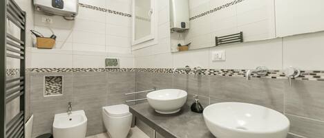 Un baño moderno con dos lavamanos, un bidé y un espejo.