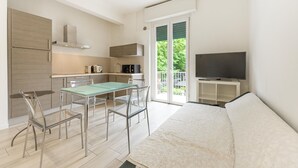 A compact living space with a kitchenette, dining area, and a balcony with a TV. - Roberto Flat - 10 min da Fiera di Verona (Verona)