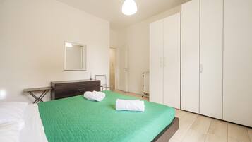 A bedroom with a bed, a dresser, a mirror, and a wardrobe.
