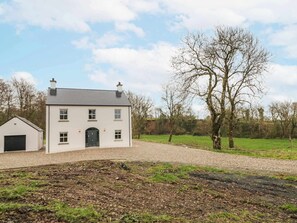 A two-story white building with a black door and windows, a small attached garage, and a gravel driveway. - Cloneytrace Mines, Broughshane (Ballymena)