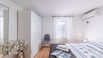 Un dormitorio moderno con cama, una silla, armario y ventana con cortinas translúcidas.