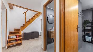 A modern interior with a wooden staircase, a round mirror, and a minimalist bathroom.