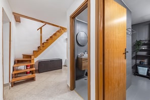 A modern interior with a wooden staircase, a round mirror, and a minimalist bathroom. - Hidden Hill Lopar With Sauna & Jacuzzi (Lopar)