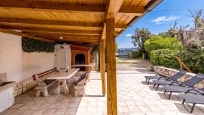An outdoor patio with a wooden pergola, stone benches, and lounge chairs. - Hidden Hill Lopar With Sauna & Jacuzzi (Lopar)