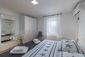 Een slaapkamer met een bed, een stoel, een spiegel, een kledingkast en een airconditioning.