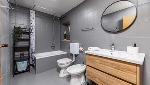 A modern bathroom with a bathtub, two toilets, a sink, a mirror, and a shower. - Hidden Hill Lopar With Sauna & Jacuzzi (Lopar)