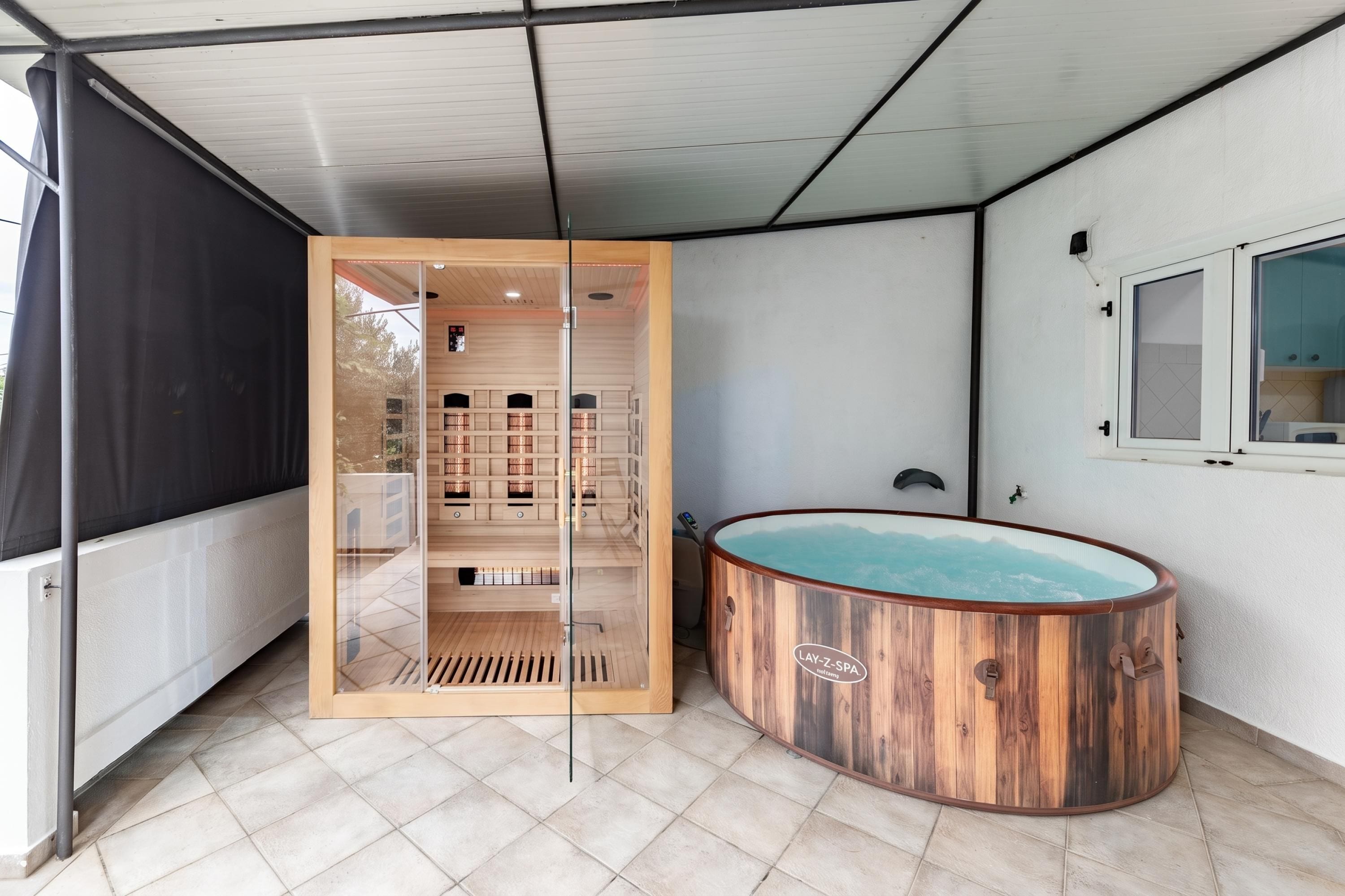 A spa area with a wooden sauna, a glass-enclosed room with shelves, and a window overlooking a mountain.