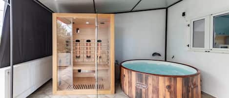A spa area with a wooden sauna, a glass-enclosed room with shelves, and a window overlooking a mountain.