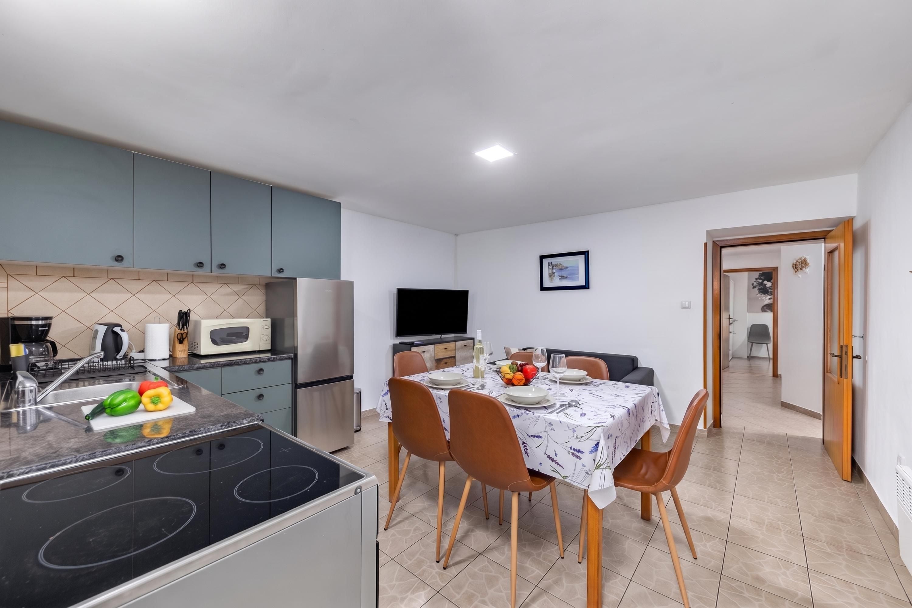 Una cocina compacta con comedor, televisor y una puerta que da a otra habitación.