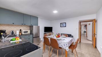 Una cocina compacta con comedor, televisor y una puerta que da a otra habitación.