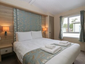 A hotel room with a large bed, two bedside lamps, a window with curtains, and a view of the outside. - Mallard is situated in Shobdon (Leominster)