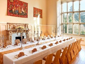 Una larga mesa de comedor preparada para un evento formal, con sillas y candelabros.