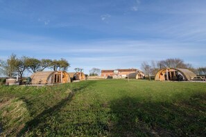 A series of dome-shaped cabins in a grassy field with a clear sky. - Glamping Pod 1 Comfort, 1 bed. (Scarborough)