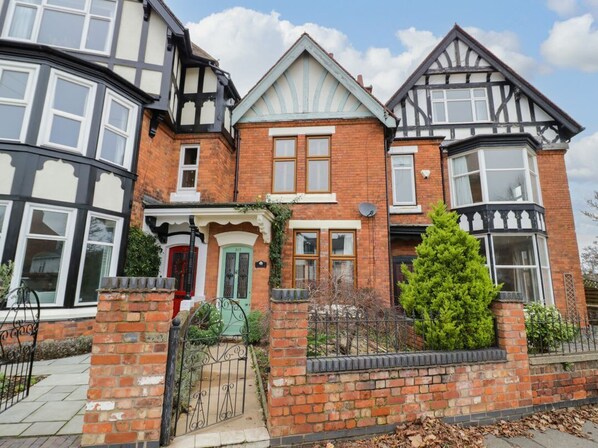 A traditional brick house with a bay window, a front door, and a small garden.