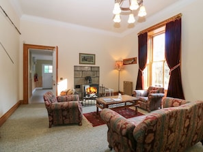 A cozy living room with patterned sofas, a fireplace, and a dining table. - Inverallan House, Grantown-On-Spey (Grantown-on-Spey)