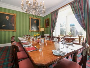 A formal dining room with a long wooden table set for a meal, flanked by chairs, and a chandelier above. - Inverallan House, Grantown-On-Spey (Grantown-on-Spey)