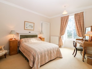 A bedroom with a bed, bedside lamps, a chair, a desk, and a window with curtains. - Inverallan House, Grantown-On-Spey (Grantown-on-Spey)