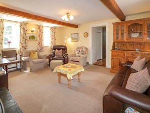 A living room with a brown leather sofa, a beige armchair, a wooden coffee table, and a wooden cabinet.