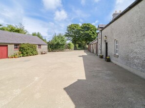 A paved driveway leading to a row of buildings with a red door on the left.