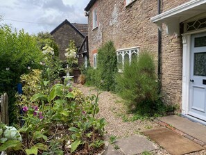 A stone house with a garden, a white door, and a visible window with white trim. - Cefn Campstone, Abergavenny (Abergavenny)
