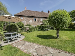 A stone house with a tiled roof, a grassy lawn, a picnic table with an umbrella, and a tree. - Cefn Campstone, Abergavenny (Abergavenny)
